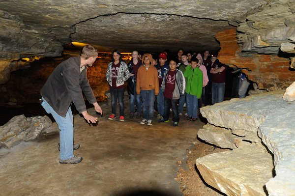 Donald Locander shows students from St. Raphael Catholic School in Springdale how they would have needed to crawl to see this portion of the cave before it was opened up during an expansion project. Workers used dynamite to open a 94-foot tunnel to a part of the cave that contains formations and a lagoon. 