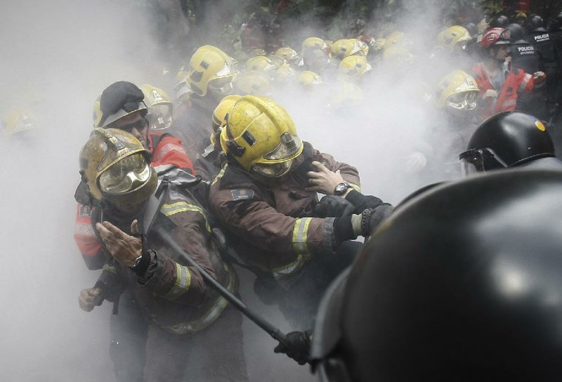 Police charge at firefighters Wednesday during a protest of austerity measures in front of the Catalunya Parliament in Barcelona, Spain. The European Union softened its focus on austerity Wednesday when it gave France, Spain and four other members more time to control their budget deficits. 
