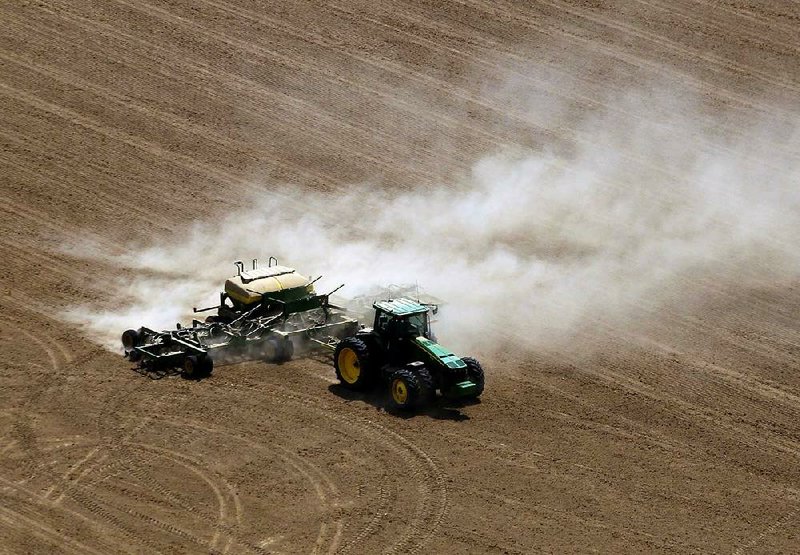 A farmer plants rice near Carlisle in Lonoke County on May 8. Cool wet weather has put Arkansas farmers behind in planting the state’s corn crop, which was 99 percent completed by the end of last week. 