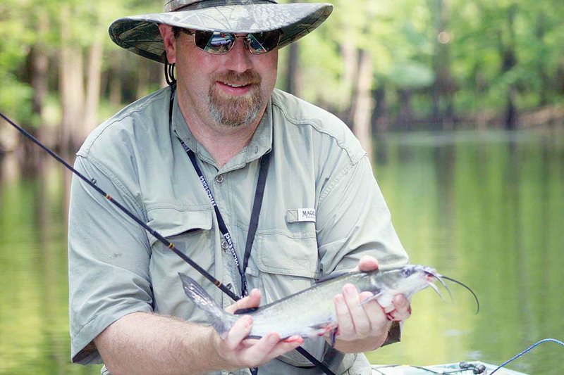 Little Rock angler Kenneth Mayes holds a frying-size channel catfish taken from an oxbow lake along the lower White River in eastern Arkansas. Many catfish anglers believe that the worse their bait smells, the better the fish will bite.