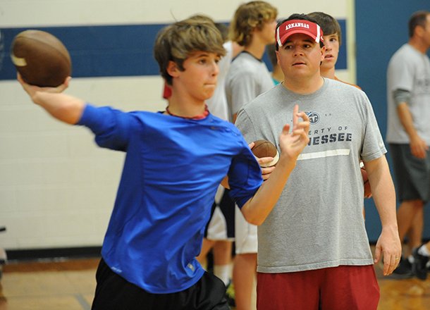 Former Arkansas quarterback and current offensive coordinator for the Tennessee Titans Dowell Loggains works with camper Adam Saveall, 13, of Fayetteville Saturday, Jun. 1, 2013, at Woodland Junior High School in Fayetteville.