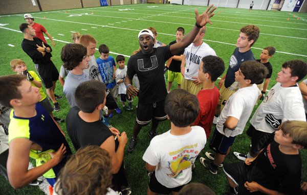 Michael Irvin, a former Dallas Cowboys receiver and current NFL analyst speaks with campers Sunday during the Northwest Arkansas Passing Academy football camp at Fayetteville High School. 