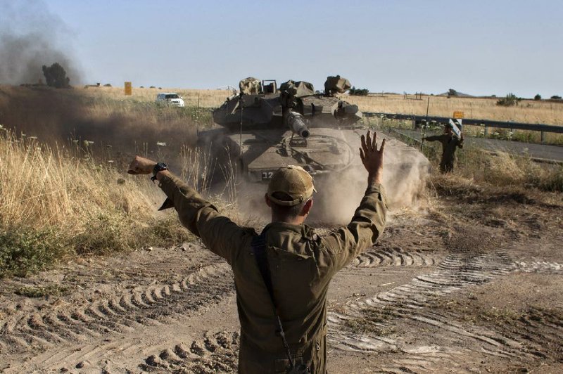 An Israeli soldier directs a tank Thursday near the Quneitra crossing in the Golan Heights, where Syrian rebels had captured a crossing point. 