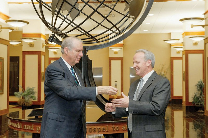 Former Harding University President David Burks, left, hands an office key to Bruce McLarty, signifying the transfer of the presidency at Harding to McLarty. Burks will now serve as chancellor at the school.