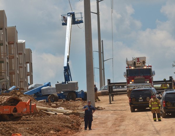 Fayetteville emergency responders try to reach two construction workers on top of a boom lift after it made contact with a power line at the Vue apartments under construction on Stadium Drive. One man died and three other workers were transported to Washington Regional Medical Center. 