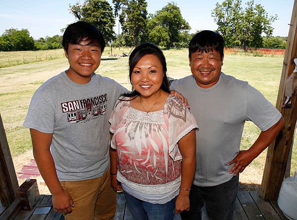 Washington County Farm Family of the year Cindy and David Yang stand with their son Pao, left, 15, on their farm in Summers . The Yangs also have two daughters Maly, 20, and PaFoua, 18, and another son Johnny, 17. The family owns 50 acres and works six chicken houses. 