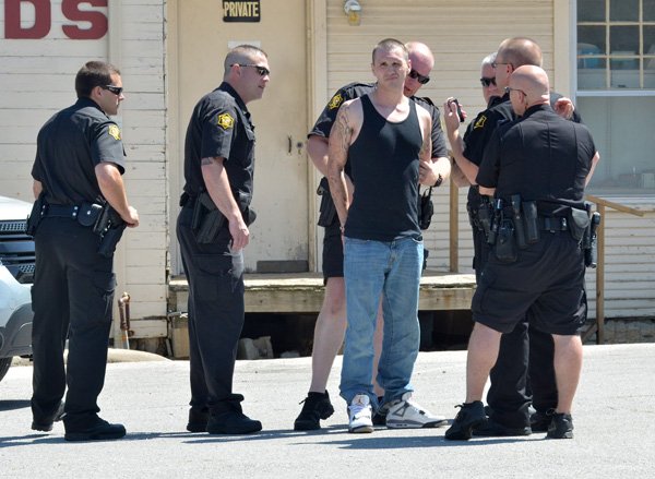 Springdale police officers take Noah Dillaplane into custody Tuesday in the parking lot in front of the J&S Taxes office on the 200 block of South Thompson in Springdale. Dillaplane, police said, tried to shoot another man in the parking lot of the Advance Auto Parts store a block away, but was caught trying to hide in the tax office building after asking to use their phone. 