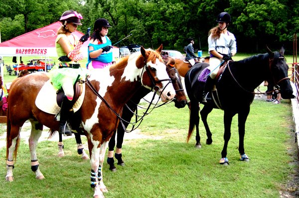 Avery Wilson, atop Fresco Di Sorento (left), Morgan Moore, riding Sonny Skippa Partner, and Megan Wadley, with Empire Strikes Back, dress in '80s fashion, the theme of this year’s Hunter/Jumper show at Legends Equestrian Center east of Decatur on June 1. The girls, students of Heather Swope, were reviewing the course layout. 
