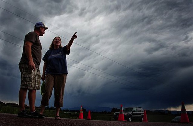 Jasen Dill, left, and Judy Pohlod discuss returning to their homes, which made it through the Black Forest fire safely, as a storm passes overhead at the corner of Hodgen Road and Highway 83 Friday, June 14, 2013 in Colorado Springs, Colo.