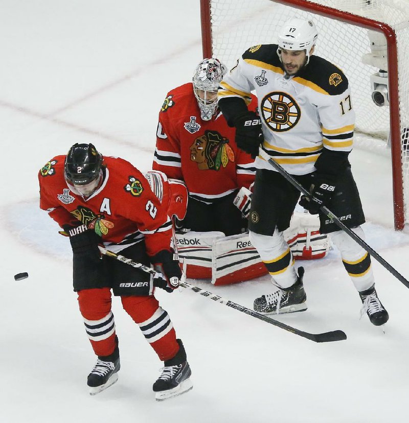Chicago defenseman Duncan Keith (2) uses his body to block a shot as Blackhawks’ goalie Corey Crawford (50) defends while Boston Bruins left wing Milan Lucic (17) waits for a deflection during the Bruins 2-1 overtime victory Saturday night in Chicago. 