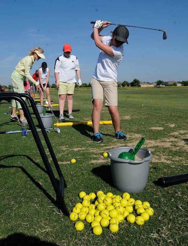 Baylee Maes, right, practices her swing Tuesday at First Tee golf center in Lowell. 