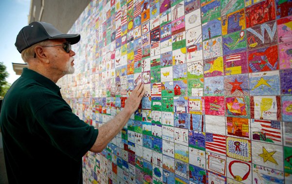 Wayne Anderson of Columbia, Mo., looks over the “Wal-Art” mural Thursday off the square in Bentonville. With the help from Bentonville elementary students, the mural was created by Connecticut artist Brendan O’Connell. 