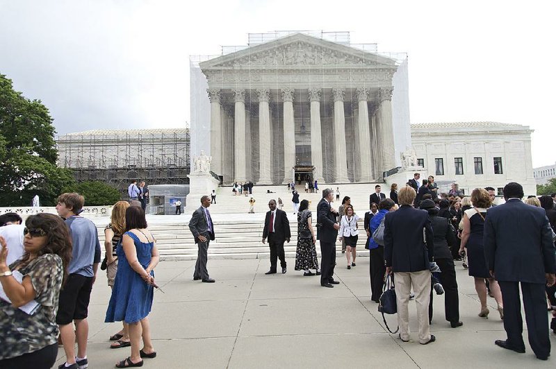 People wait outside the Supreme Court in anticipation of key decisions being announced Monday in Washington. 