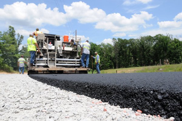 Crew members from Benton County’s Road Department lay asphalt Wednesday on North Tillys Hill Road near Decatur. The county recently began using asphalt with recycled tires to pave roads. 