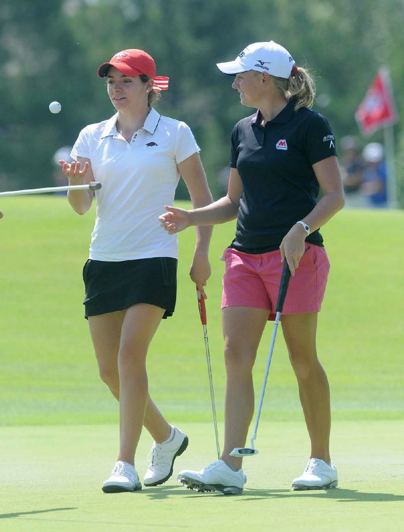 Former Arkansas golfer Stacy Lewis (right), a volunteer coach for the Razorbacks and the second-ranked golfer in the world, talks with Arkansas golfer Gaby Lopez after finishing on the first green during Thursday’s Pro-Am at the Wal-Mart Northwest Arkansas Championship at Pinnacle Country Club in Rogers. Lewis has had a busy week, between hosting the Stacy Lewis Junior Open across town and helping Lopez prepare for today’s opening round.

