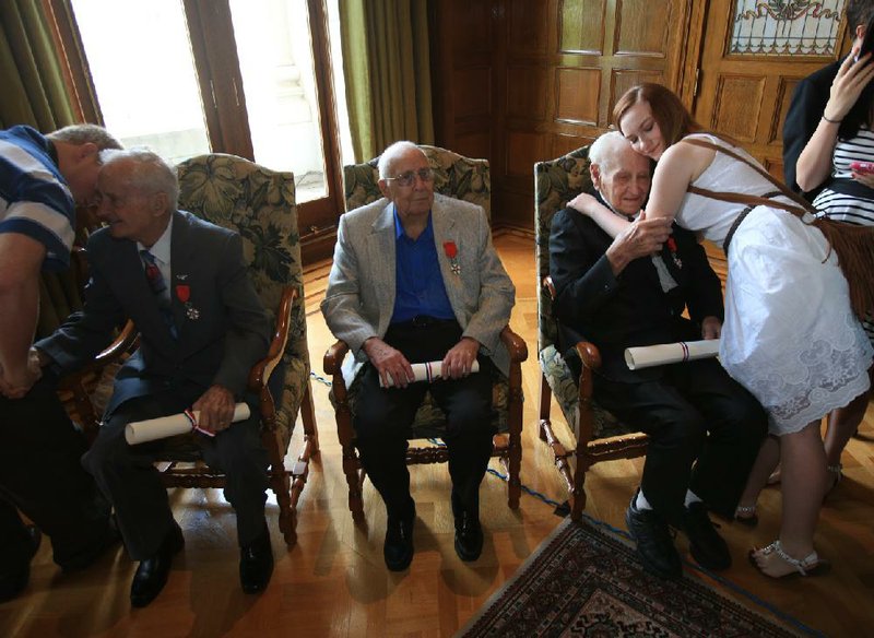 Lawson May hugs her great-grandfather, Charles Lawson, Thursday morning after he received the Legion of Honor medal. Three liberators who fought Nazi Germany on French soil, Lawson, Daniel Towery (seated left) and Harlow Conrad (center), received the honor at the state Capitol in Little Rock. 