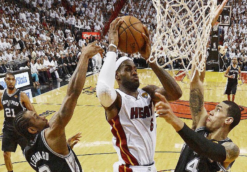 Miami’s LeBron James (center) scores two of his game-high 37 points, going over San Antonio’s Danny Green (4) in the Heat’s 95-88 victory Thursday in Game 7 of the NBA Finals. James, the series and regular-season MVP for a second consecutive year, also had 12 rebounds. It was the Heat’s third NBA title. 