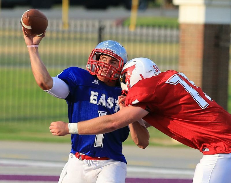 Arkansas Democrat-Gazette/RICK MCFARLAND --06/21/13--  The East's Sterling Stowers, Highland, is hit as he releases a pass by the West's McKinzie James (75), Camden Fairview, in the East West All Star football game at UCA Friday.