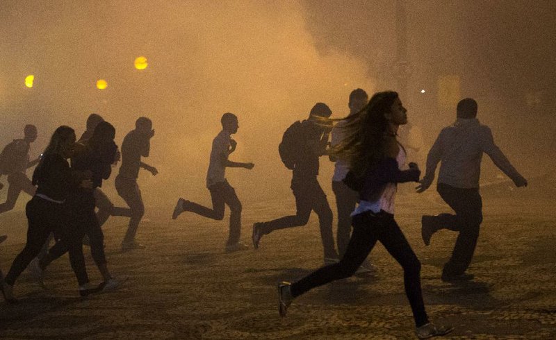 Protesters run from the clouds of tear gas during an anti-government protest in Rio de Janeiro, Brazil, Thursday, June 20, 2013. Police and protesters fought in the streets into the early hours Friday in the biggest demonstrations yet against a government viewed as corrupt at all levels and unresponsive to its people. (AP Photo/Victor R. Caivano)
