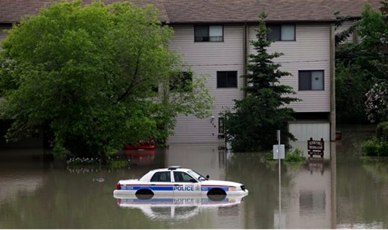A police car sits stuck in a parking lot of an apartment building after heavy rains have caused flooding, closed roads, and forced evacuation in Calgary, Alberta, Canada Friday, June 21, 2013.