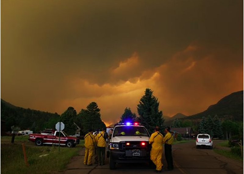 Firefighters stage in a residential area in South Fork, Colo., as they monitor a wildfire that burns west of town on Friday evening June 21, 2013. The town was evacuated and U.S. 160 that passes through it was closed.