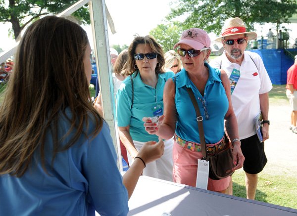 Hannah Baroni, from left, explains Friday to Mary Arce, Marica Azan and Ray Arce how to use the free pedometers Mercy Northwest Arkansas was giving away on the 17th hole at Pinnacle Country Club in Rogers during the Walmart NW Arkansas Championship. Mercy came prepared with 2,000 pedometers to give away along with hosting a sunscreen station and blood pressure station. 