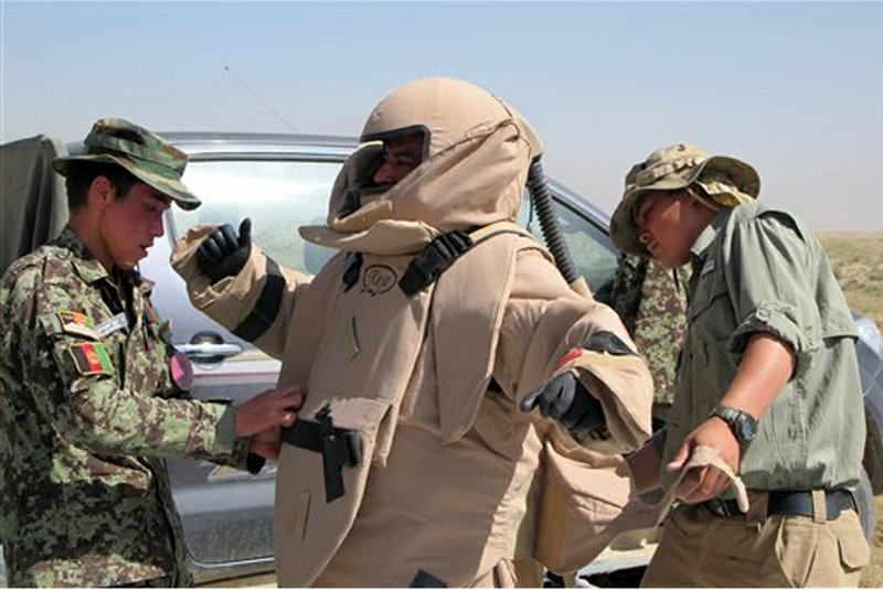 In this Tuesday, June 11, 2013 photo, Hayatullah, center, is fitted with a protective suit before inspecting a land minee during a bomb defusing training exercise on the outskirts of Kabul, Afghanistan. A few years ago, there were almost no Afghan bomb disposal experts. Now, there are 369 — and the international coalition is rushing to train hundreds more before the exit of most coalition forces by the end of next year. 