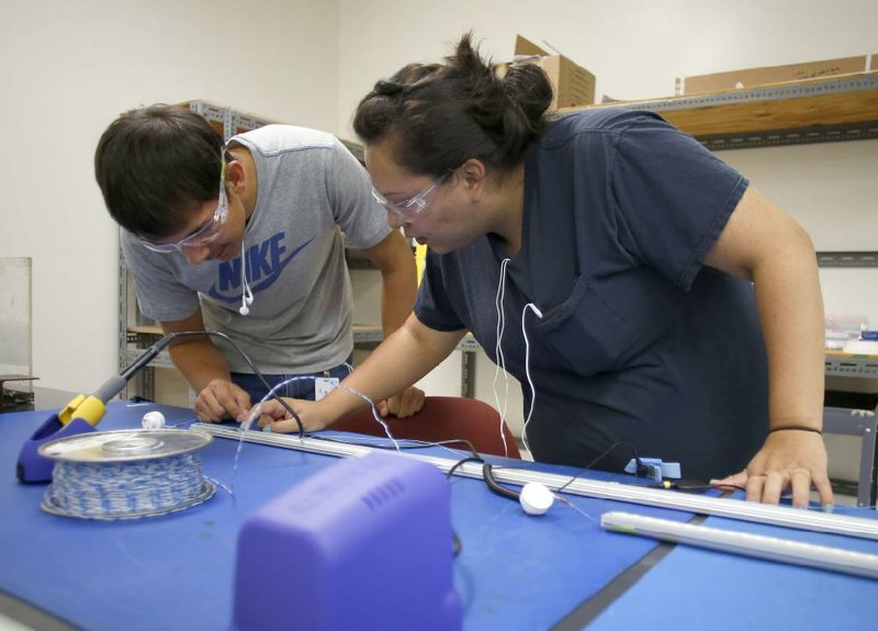 NWA Media/DAVID GOTTSCHALK

6/20/13

Marcus Chuculate (cq) (left) and Krystal Tiger, both production associate B, look at components on the assembly line of the Next Gen LED Thursday morning at Cherokee Nation Industries in Stillwater, Okla. The plant will begin assembling the lighting Monday at the facility.