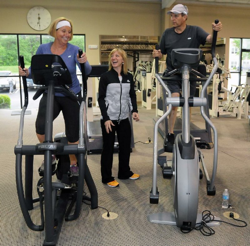 Fitness instructor Cindy Velotta (center) keeps Karen Dineen (from left) and Tom Johnson inspired while they trudge up and down on ellipticals May 23 at the Northwest Arkansas Mercy Family YMCA. All are cancer survivors participating in LiveStrong at the YMCA. 