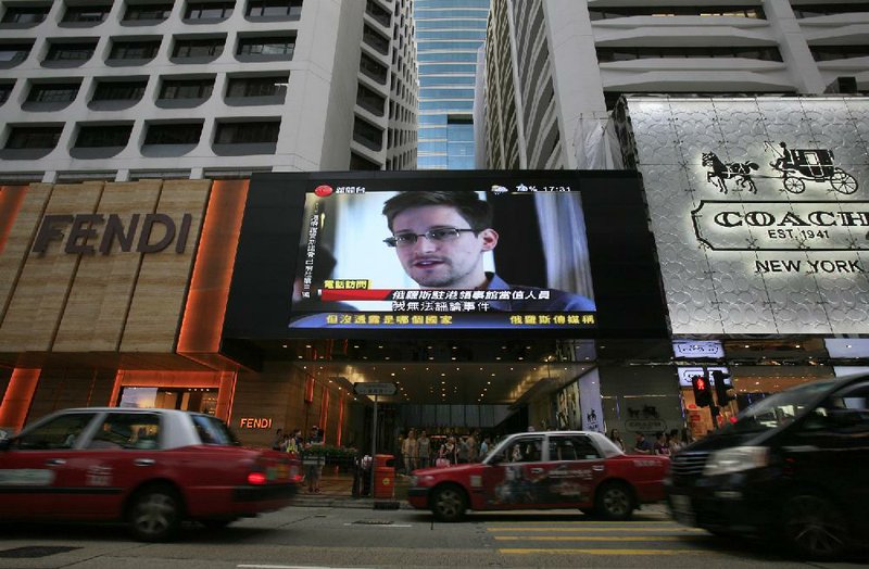 A TV screen shows a news report of Edward Snowden, a former CIA employee who leaked top-secret documents about sweeping U.S. surveillance programs, at a shopping mall in Hong Kong Sunday, June 23, 2013. The former National Security Agency contractor wanted by the United States for revealing two highly classified surveillance programs has been allowed to leave for a "third country" because a U.S. extradition request did not fully comply with Hong Kong law, the territory's government said Sunday. (AP Photo/Vincent Yu)