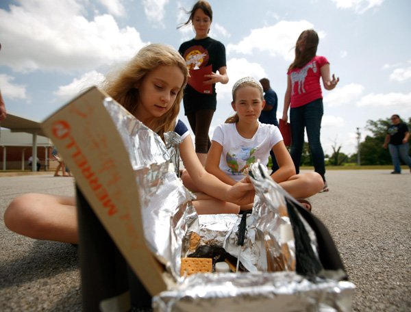 Teaghan Wharry, from left, 10, Mesa Matlock, 12, Anna Mays, 11, and Morgan Dunn, 13, monitor their designed solar oven as it cooks s’mores Monday outside Tyson Middle School in Springdale. The girls are participating in the I Do Science Camp. 