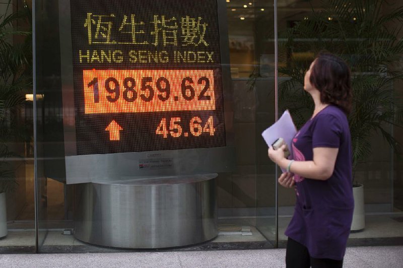 A pedestrian passes the Hang Seng Index figure displayed on an electronic board at a bank in Hong Kong on Tuesday. China’s central bank confirmed Tuesday that it took steps last week to ease lending between banks. 