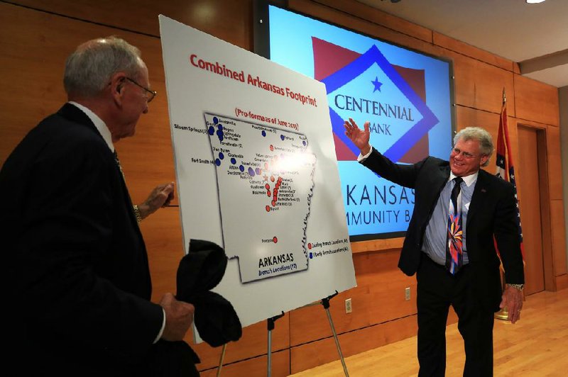 Wallace Fowler (left) of Liberty Bancshares and John Allison of Home BancShares unveil a map Tuesday at the Little Rock Regional Chamber of Commerce that shows the branch locations of the two banks (see graphic associated with article). 