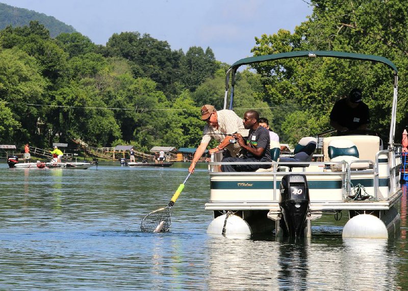 Fishing guide Jerry Poplin (left) helps Army veteran James Felton land a trout Tuesday morning near Lobo Landing on the Little Red River during a fishing retreat for veterans organized by the United Methodist Men of Heber Springs’ First United Methodist Church and the nonprofi t Arkansas Freedom Fund, which provides outdoor activities for veterans. 