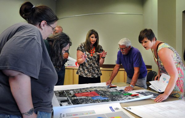 Shelli Kerr, center, Bentonville planning service manager, answers questions Wednesday from residents and business owners about plans for specialized districts in the southeast portion of downtown at the Bentonville Public Library. 
