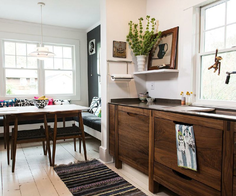 AT HOME for release JUNE 2013 BY DESIGN H-3: Certified kitchen designer Susan Serra devised a built-in, L-shaped banquette with a "super cushy" 5-inch-thick pad at the far end of the kitchen's dine-in space. The shape of the tabletop, done in Silestone, was patterned after Serra's mother's vintage mid-century modern table, which serves as the base. Walnut furniture-like, Scandinavian-inspired kitchen cabinets (Serra's design) are simple, modern and warm. The Silestone countertop is from Cosentino, chosen in a complementary dark color and given a reverse bevel edge with a minimal overhang to look like a piece of furniture. Space-saving devices include rails and floating shelves that lift accoutrements off of the counter for maximal accessibility. 