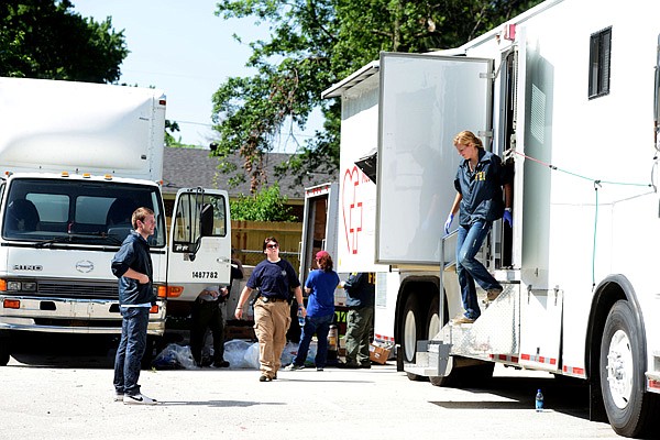 Agents from the Federal Bureau of Investigation search motor coaches at Situs Cancer Research Center Thursday on Poplar Street in Rogers. They removed office and medical equipment from the vehicles. 