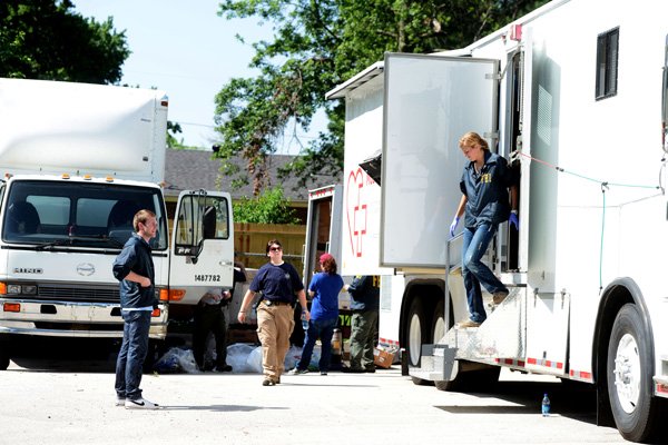 Agents from the Federal Bureau of Investigation search motor coaches at Situs Cancer Research Center Thursday on Poplar Street in Rogers. They removed office and medical equipment from the vehicles. 