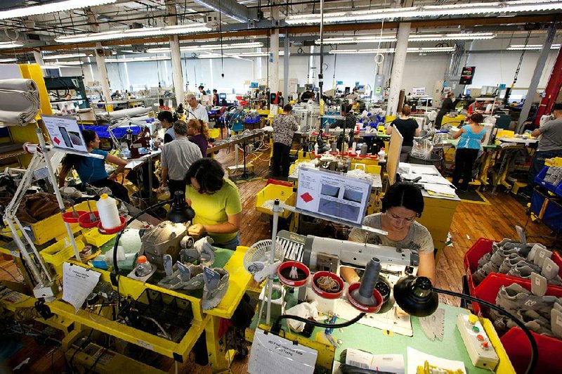 Workers assemble sneakers in the New Balance Athletic Shoe, Inc. factory where the majority of the production is done by hand in Lawrence, Massachusetts, U.S. on Friday, Dec. 16, 2011. A shoe that would take about 20 minutes to make in Asia takes two and half minutes to make in the U.S., according to New Balance Chief Executive Officer Robert DeMartini. "The way we make shoes in the U.S. delivers the same or higher quality at a much lower labor content rate, " he said in September. Photographer: Scott Eisen/Bloomberg
