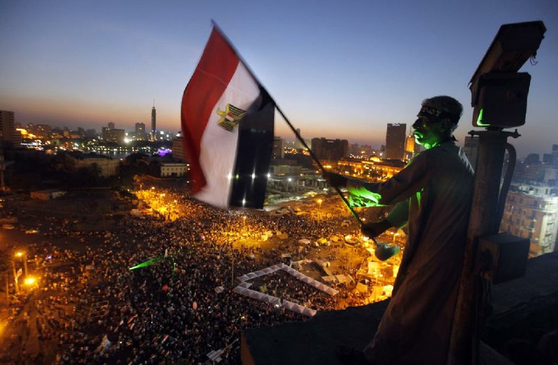 An Egyptian protester waves a national flag over Tahrir Square, the focal point of Egyptian uprising as opponents of President Mohammed Morsi are gathered in Cairo, Egypt, Friday, June 28, 2013.  Tens of thousands of backers and opponents of Egypt's Islamist president held competing rallies in the capital Friday and new clashes erupted between the two sides in the country's second largest city, Alexandria, in a prelude to massive nationwide protests planned by the opposition this weekend demanding Mohammed Morsi's removal. (AP Photo/Amr Nabil)