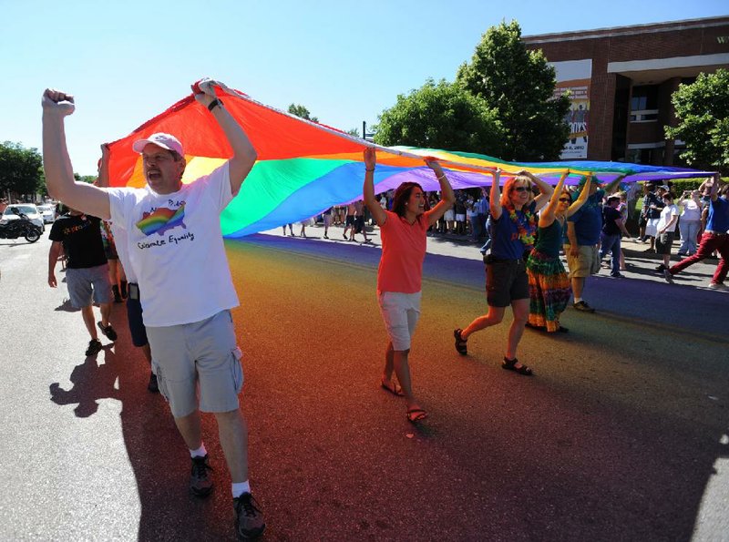 Arkansans carry a rainbow flag Saturday in the seventh annual NWA Pride Parade to support gay rights. Organizers said this year’s rally had special significance because of the U.S. Supreme Court ruling allowing legally married same-sex couples to receive federal benefits. 