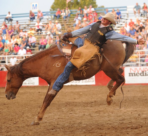 Cody Mounts of Pine Bluff hangs on July 6 during the Rodeo of the Ozarks’ bareback riding competition at Parsons Stadium in Springdale. 