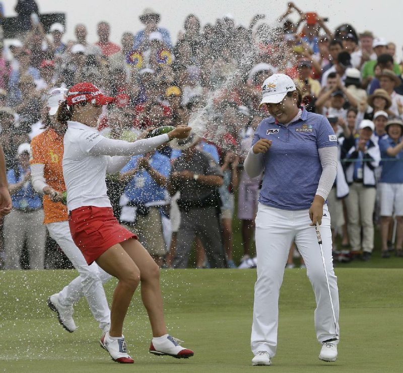 Inbee Park (right) is sprayed with champagne after sinking her last putt during the final round of the U.S. Women’s Open. Park shot 8-under-par 280 for her third major victory of the season. 