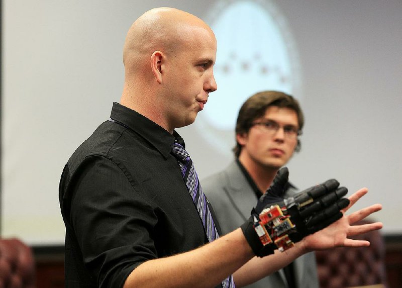 University of Central Arkansas students John White (left) and Kyle Eichelberger explain the Bear Claw System, a glove designed to help with physical and occupational therapy, during a demonstration Tuesday. 