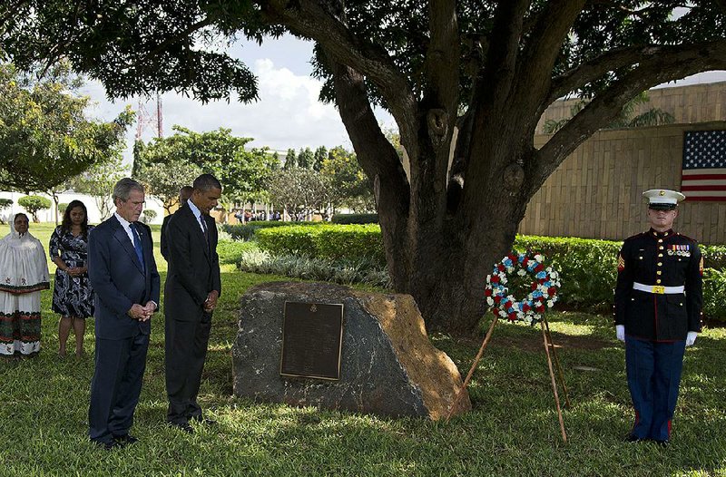 Former President George W. Bush and President Barack Obama observe a moment of silence Tuesday during a wreath-laying ceremony for the victims of the 1998 embassy bombing in Dar es Salaam, Tanzania. Obama left Africa for home soon after as administration officials announced a delay in parts of Obama’s health-care initiative. 