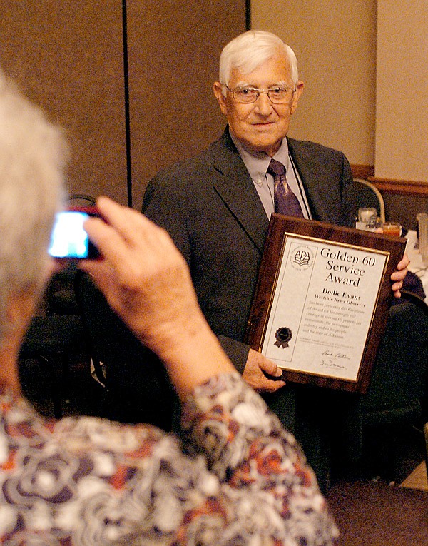 Dodie Evan’s wife, Louise, takes a photo of him after he was awarded a plaque at the Arkansas Press Association Convention, honoring him for 60 years of service in the newspaper industry 