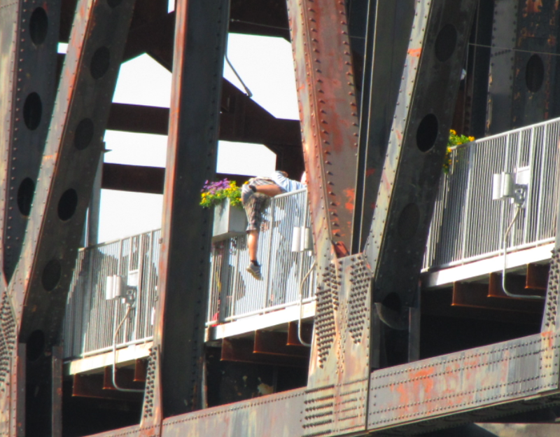 A man who had been threatening to jump from the Clinton Bridge climbs back over the rail to safety Wednesday afternoon.