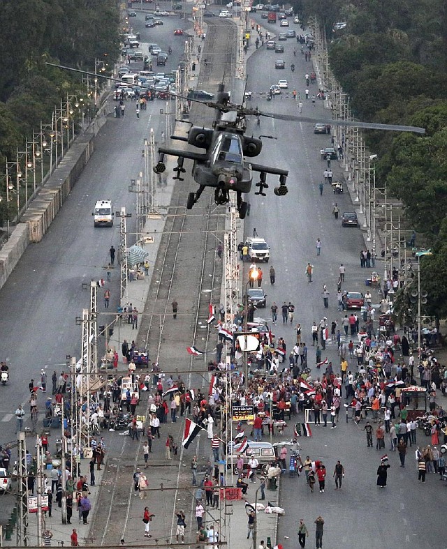A military attack helicopter flies over a street near the presidential palace, in Cairo, Egypt, Friday, July 5, 2013. The top leader of Egypt's Muslim Brotherhood has vowed to restore ousted President Mohammed Morsi to office, saying Egyptians will not accept "military rule" for another day. General Guide Mohammed Badie, a revered figure among the Brotherhood's followers, spoke Friday before a crowd of tens of thousands of Morsi supporters in Cairo. A military helicopter circled low overhead. (AP Photo/Hassan Ammar)