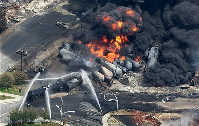 Smoke rises from railway cars that were carrying crude oil after derailing in downtown Lac Megantic, Quebec, Canada, Saturday, July 6, 2013. A large swath of Lac Megantic was destroyed Saturday after a train carrying crude oil derailed, sparking several explosions and forcing the evacuation of up to 1,000 people.