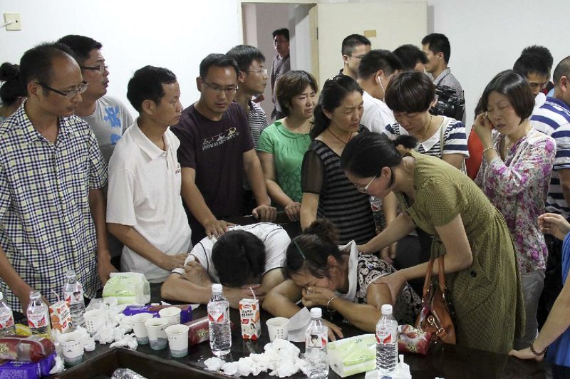 The parents (center) of Wang Linjia, one of two people who died, are comforted by parents of other students who were on Asiana Airlines Flight 214, which crashed at San Francisco International Airport, at Jiangshan Middle School in the city of Jiangshan, China, on Sunday. 